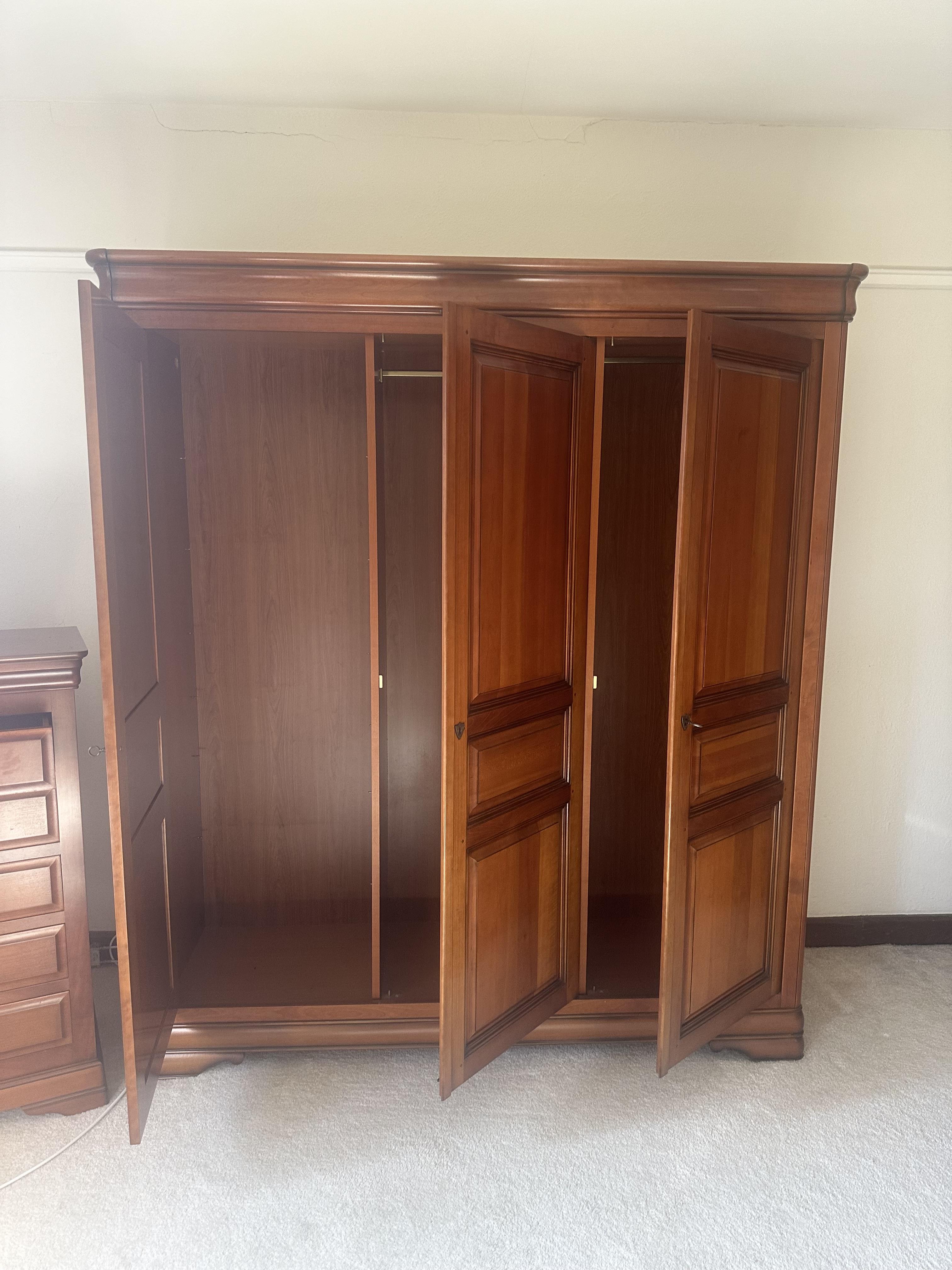 A French style cherry five piece bedroom suite, comprising triple wardrobe, four drawer chest, tall five drawer chest and a pair of bedside cabinets